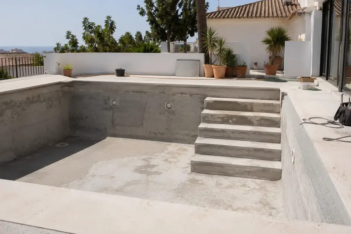 Vaso de piscina de hormigón con escalera recta de obra en construcción en un chalet de Vélez Málaga, Málaga.