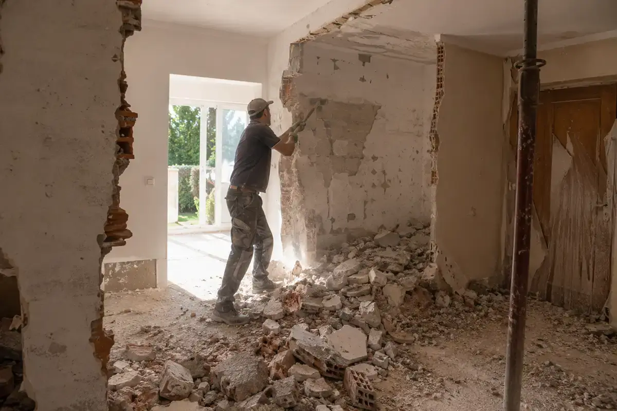 Operario con maza realizando la demolición de un tabique interior en una vivienda en reforma en Málaga.