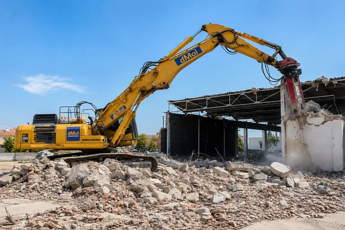 Excavadora de gran tonelaje demoliendo la estructura de hormigón de una nave industrial en un polígono de Málaga.