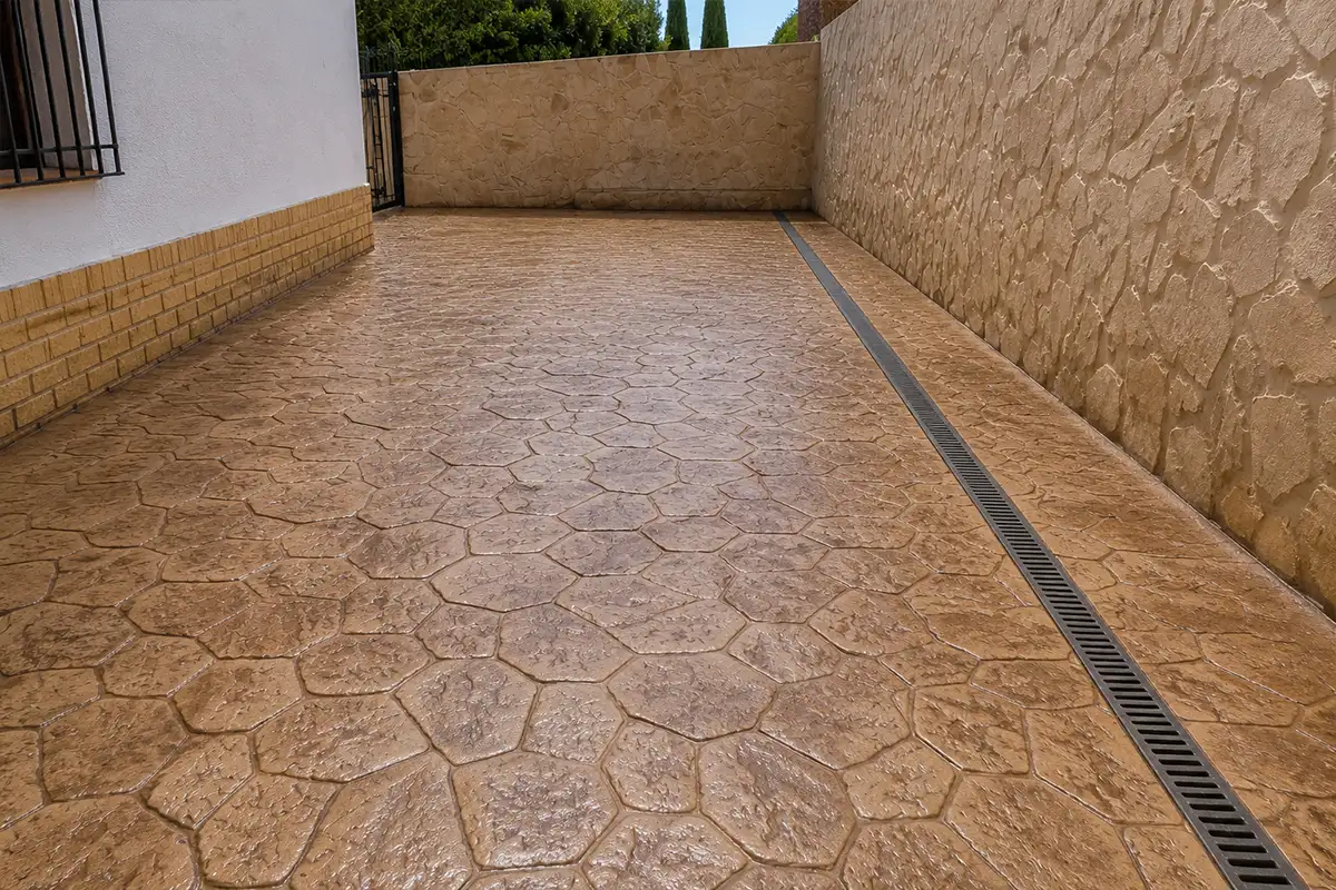 Hormigón impreso en Málaga con molde de piedra irregular en patio junto a canaleta de drenaje